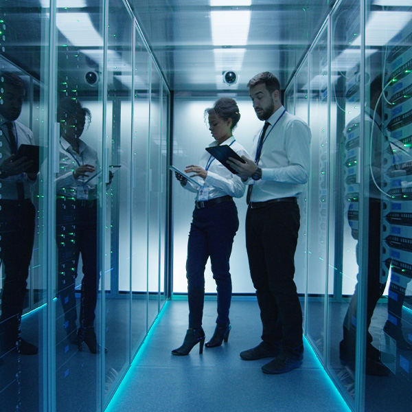 A group of skilled technicians in blue uniforms work collaboratively on server racks in a clean data center environment.